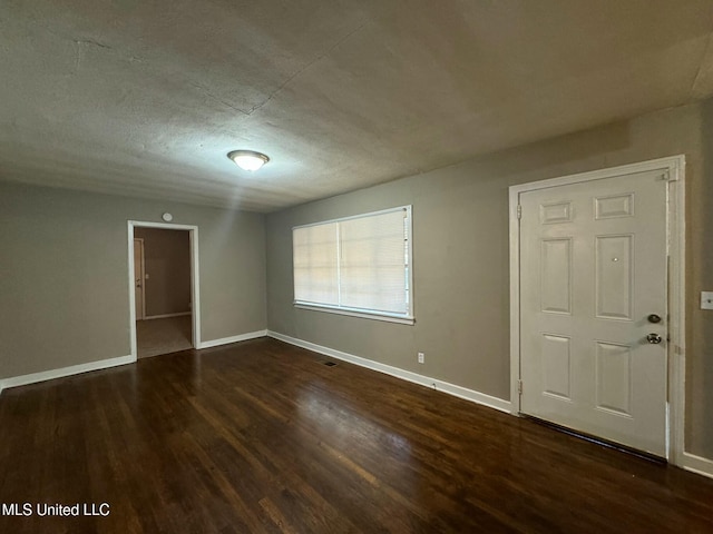 empty room with a textured ceiling and dark hardwood / wood-style floors