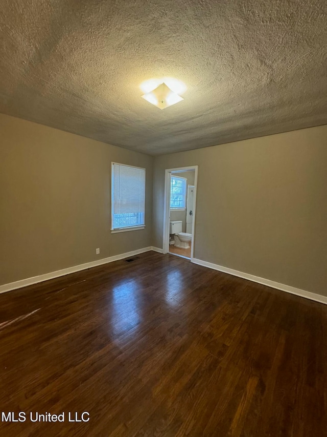 unfurnished room featuring a textured ceiling and dark hardwood / wood-style floors