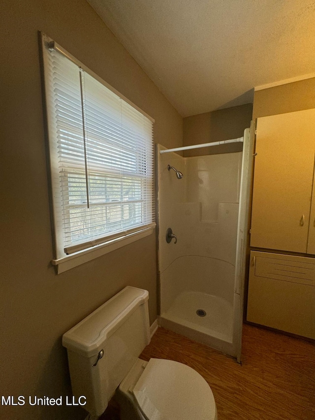 bathroom featuring toilet, hardwood / wood-style floors, a textured ceiling, and tiled shower