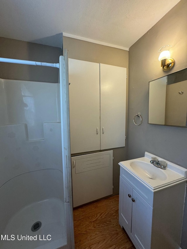 bathroom featuring hardwood / wood-style floors, vanity, walk in shower, and a textured ceiling