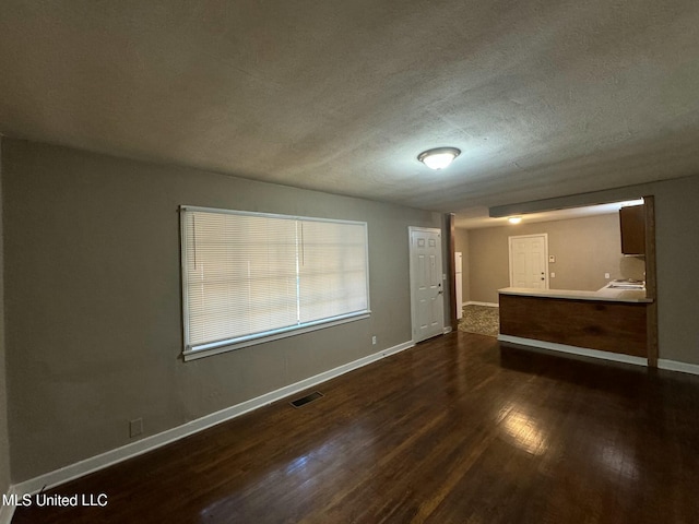 unfurnished room with a textured ceiling and dark wood-type flooring