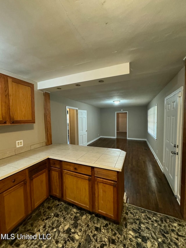 kitchen with kitchen peninsula, tile counters, and dark hardwood / wood-style floors