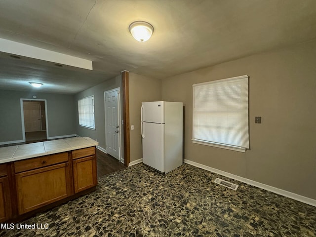 kitchen featuring tile counters and white fridge