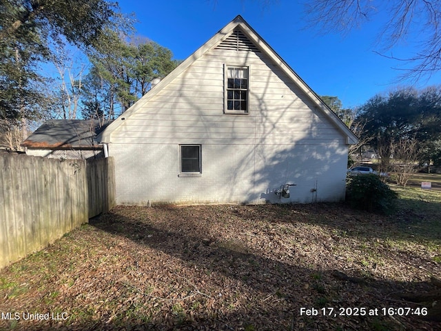 view of side of home featuring brick siding and fence