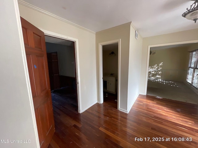 hallway featuring visible vents, wood finished floors, and baseboards