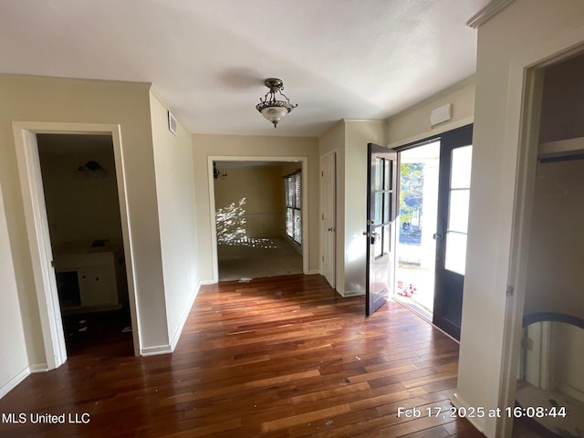 hallway with hardwood / wood-style flooring, baseboards, and visible vents