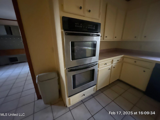 kitchen featuring light tile patterned floors, double oven, white cabinetry, and light countertops