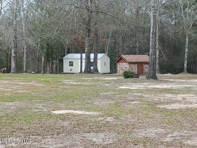 9900 Little Buck, Vancleave, MS 39565 - view of yard featuring a storage unit, an outbuilding, and a forest view