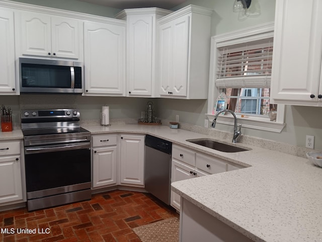 9900 Little Buck, Vancleave, MS 39565 - kitchen featuring stainless steel appliances, a sink, brick flooring, and white cabinetry