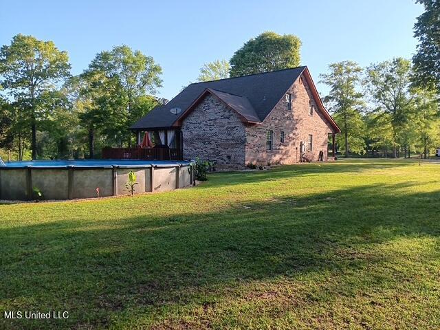 9900 Little Buck, Vancleave, MS 39565 - rear view of house with a lawn, stone siding, and a covered pool