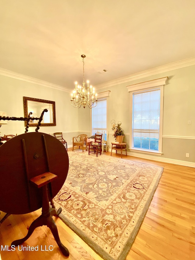 sitting room featuring hardwood / wood-style floors, ornamental molding, and a notable chandelier