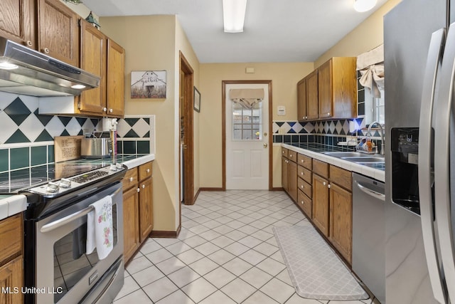 725 Bay Tree Dr, Flowood, MS 39232 - kitchen with appliances with stainless steel finishes, under cabinet range hood, tasteful backsplash, tile countertops, and brown cabinets