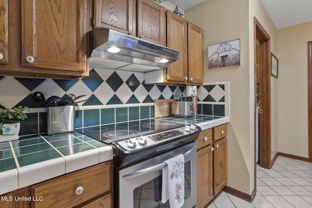 725 Bay Tree Dr, Flowood, MS 39232 - kitchen with stainless steel range with electric stovetop, under cabinet range hood, tile countertops, and brown cabinets