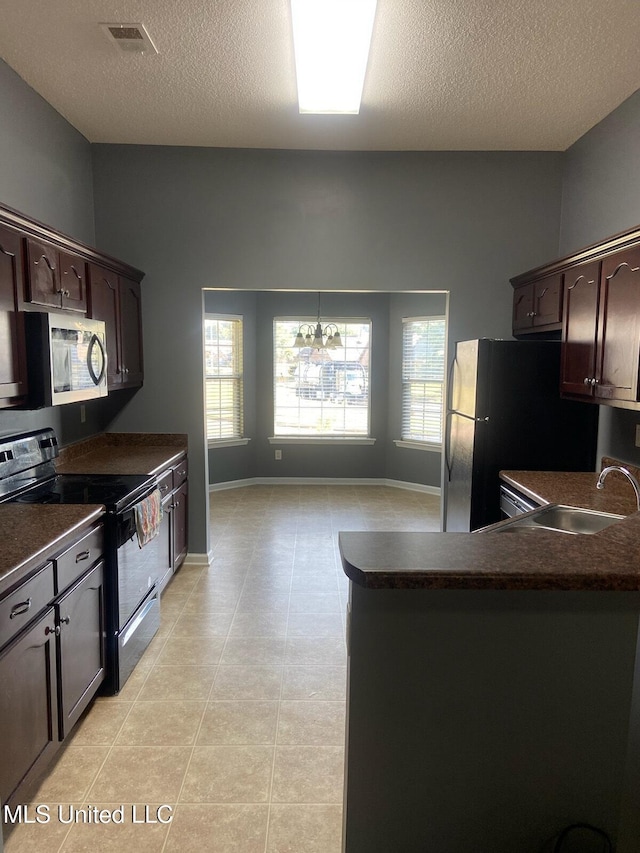 kitchen featuring dark brown cabinetry, fridge, black / electric stove, and sink