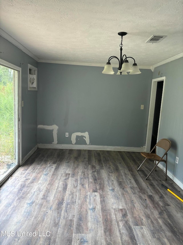 spare room with dark wood-type flooring, a textured ceiling, ornamental molding, and an inviting chandelier