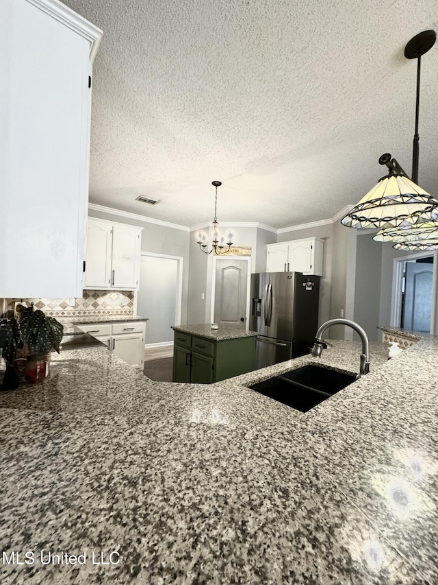 kitchen featuring sink, white cabinetry, ornamental molding, stainless steel fridge, and a kitchen island