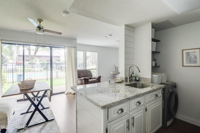 138 Molokai Vlg Unit J, Diamondhead, MS 39525 - kitchen with open shelves, a sink, ceiling fan, light stone countertops, and a peninsula