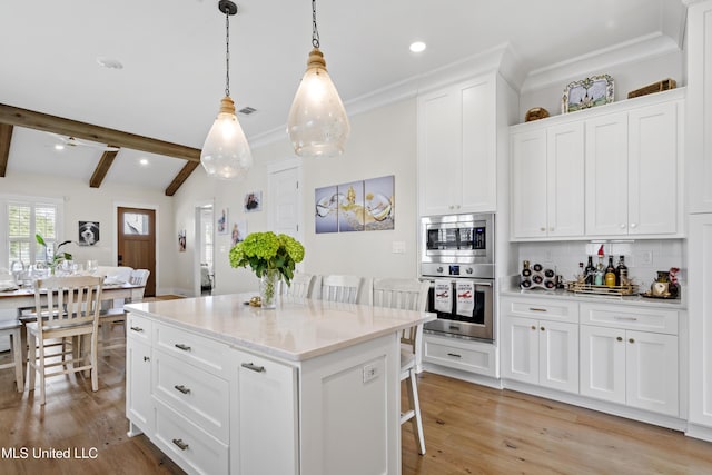 kitchen with white cabinets, a kitchen island, decorative light fixtures, backsplash, and a breakfast bar