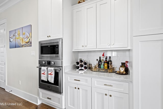 kitchen featuring dark hardwood / wood-style floors, decorative backsplash, white cabinetry, light stone countertops, and stainless steel appliances