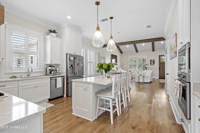 kitchen with a center island, pendant lighting, sink, white cabinetry, and appliances with stainless steel finishes