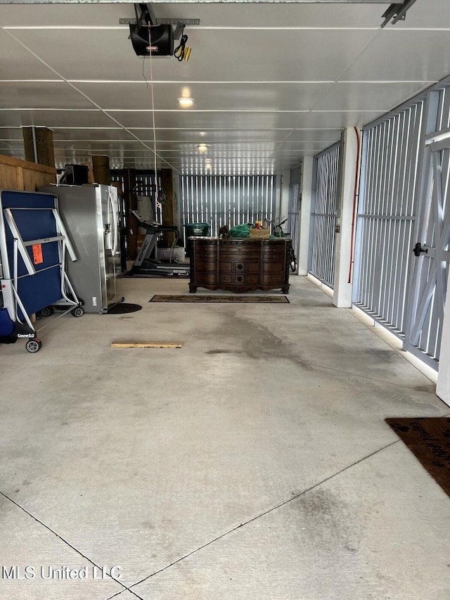 garage with a garage door opener and stainless steel fridge