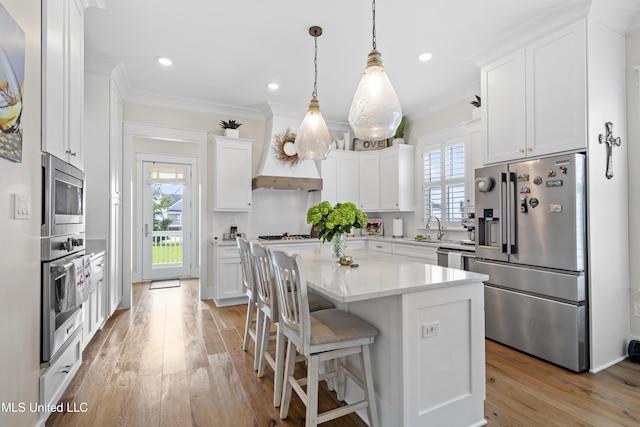 kitchen featuring decorative light fixtures, a center island, decorative backsplash, appliances with stainless steel finishes, and white cabinets