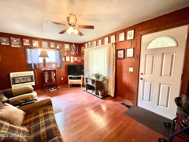 living room featuring heating unit, wood-type flooring, and ceiling fan