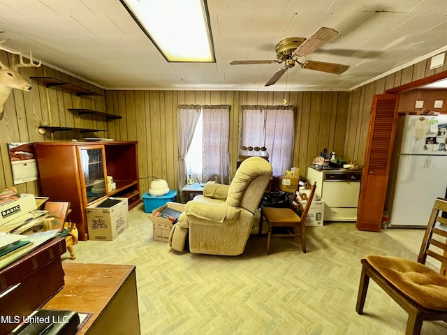 sitting room with wooden walls, light parquet floors, and ceiling fan