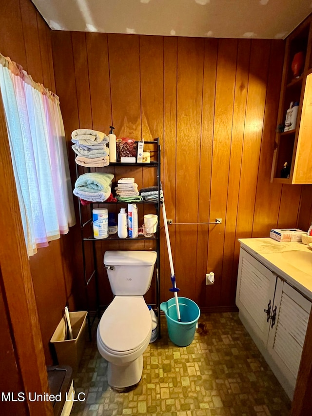 bathroom featuring vanity, toilet, and wooden walls