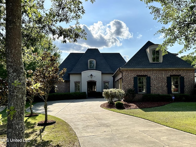 121 Vinca Dr, Madison, MS 39110 - french country inspired facade featuring curved driveway, brick siding, a front lawn, and roof with shingles