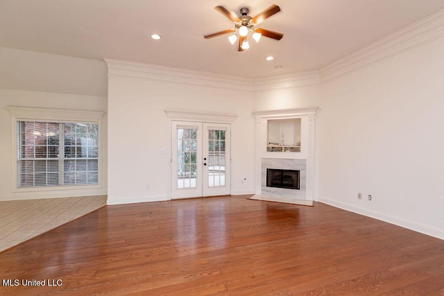 unfurnished living room with a premium fireplace, a healthy amount of sunlight, hardwood / wood-style floors, and crown molding