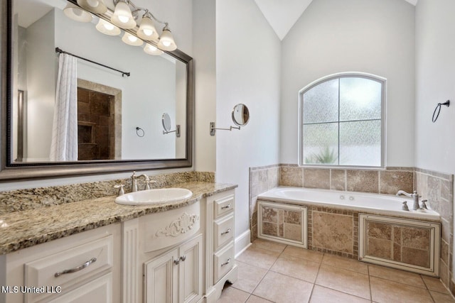 bathroom featuring vanity, vaulted ceiling, tile patterned floors, and tiled bath