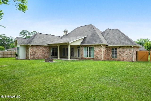 rear view of property with a yard, a patio, and an outdoor fire pit