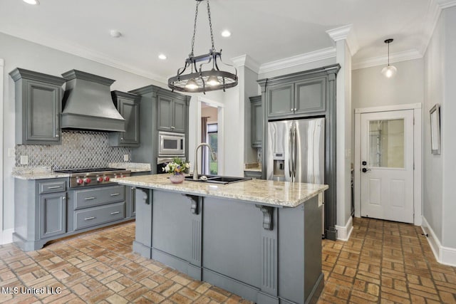 kitchen with a kitchen island with sink, premium range hood, appliances with stainless steel finishes, a breakfast bar area, and pendant lighting