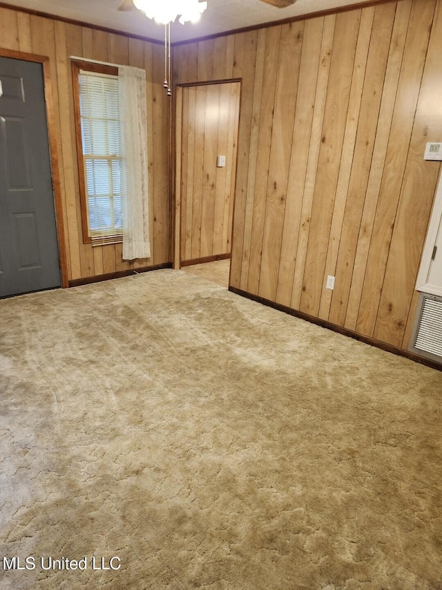 unfurnished room featuring wooden walls, carpet, and ceiling fan