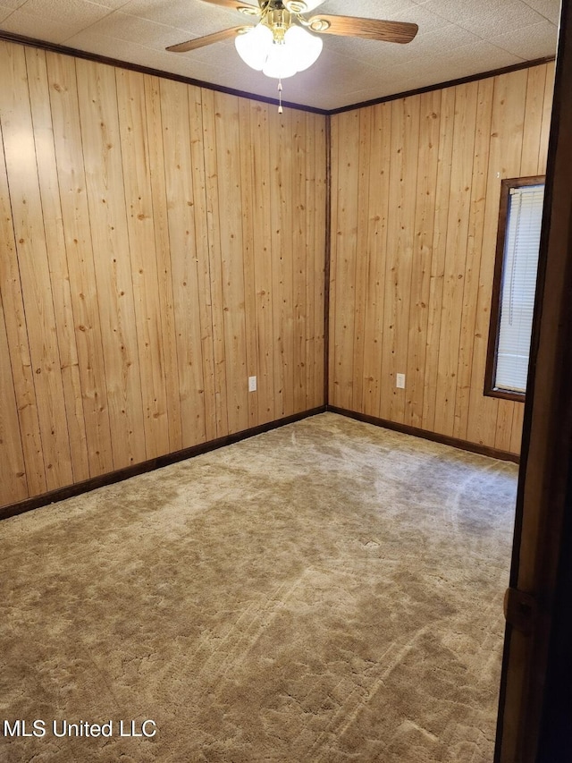 carpeted spare room with ceiling fan and wooden walls