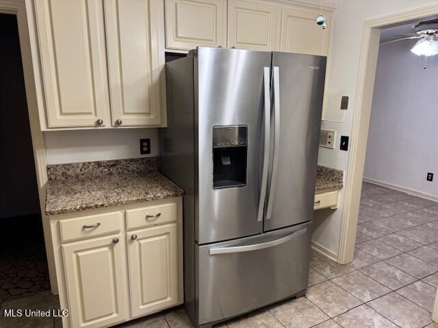 kitchen with light stone counters, light tile patterned flooring, ceiling fan, and stainless steel refrigerator with ice dispenser