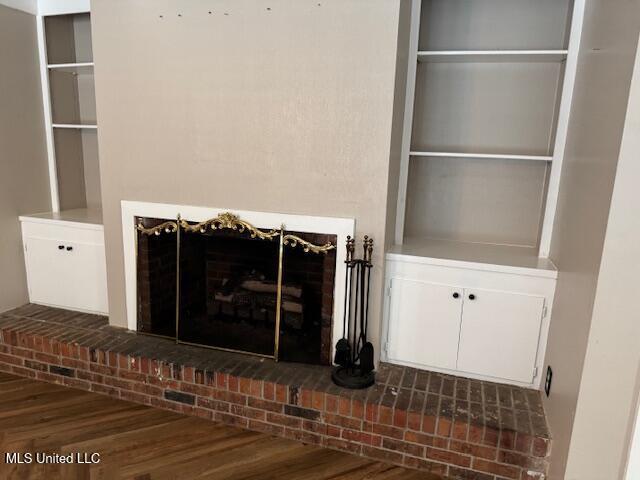 unfurnished living room featuring dark wood-type flooring, a fireplace, and built in features