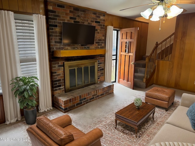 carpeted living room with ceiling fan, a fireplace, and wood walls