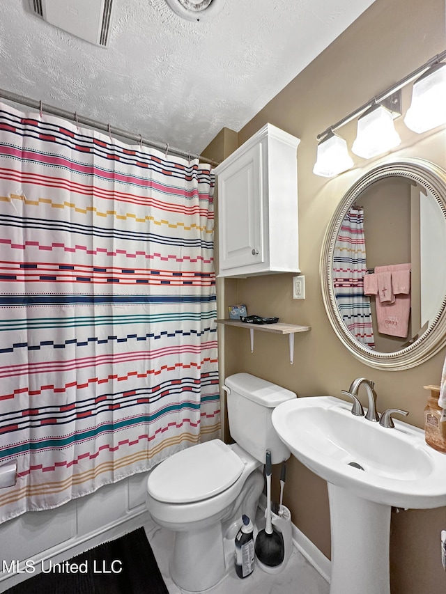 1008 Normandy Dr, Clinton, MS 39056 - bathroom featuring toilet, a textured ceiling, baseboards, a sink, and shower / bath combination with curtain