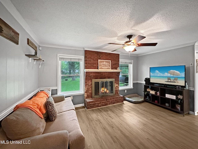1008 Normandy Dr, Clinton, MS 39056 - living area featuring healthy amount of natural light, a textured ceiling, wood finished floors, a ceiling fan, and a brick fireplace