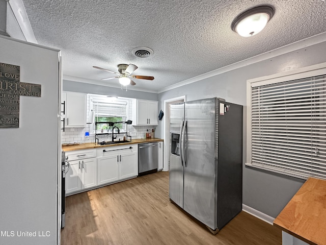 1008 Normandy Dr, Clinton, MS 39056 - kitchen featuring wooden counters, appliances with stainless steel finishes, a sink, white cabinetry, and a textured ceiling