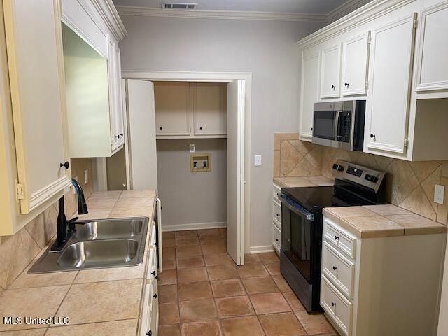 4 Foxcroft Ct, Madison, MS 39110 - kitchen with appliances with stainless steel finishes, a sink, tile counters, decorative backsplash, and white cabinetry