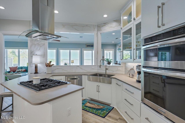 205 Audubon Point Dr, Brandon, MS 39047 - kitchen with double oven, light countertops, gas stovetop, island exhaust hood, and a sink
