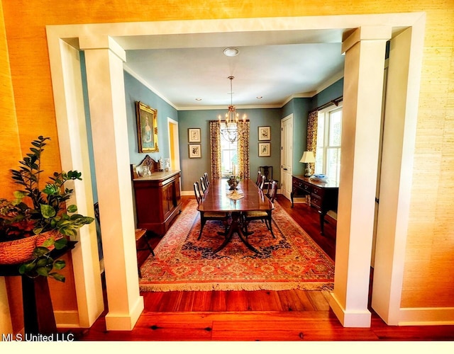 dining area with wood finished floors, a chandelier, crown molding, and baseboards
