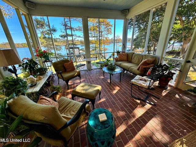 sunroom featuring a water view and brick floors