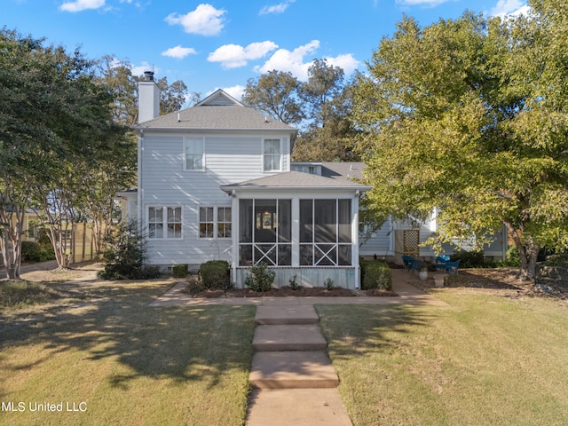 view of front of house featuring a sunroom, a chimney, a front lawn, and roof with shingles