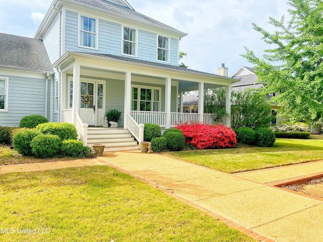 view of front of home featuring a front yard, a shingled roof, and a porch