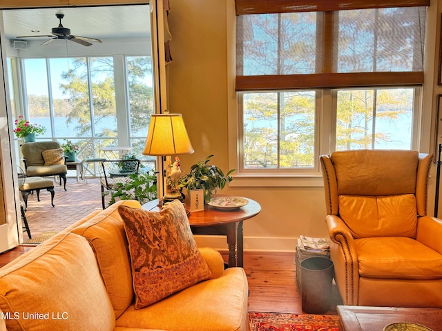 living area with wood finished floors, a ceiling fan, baseboards, and a water view