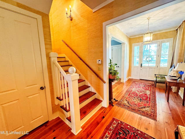 foyer with hardwood / wood-style flooring, stairs, a chandelier, and crown molding